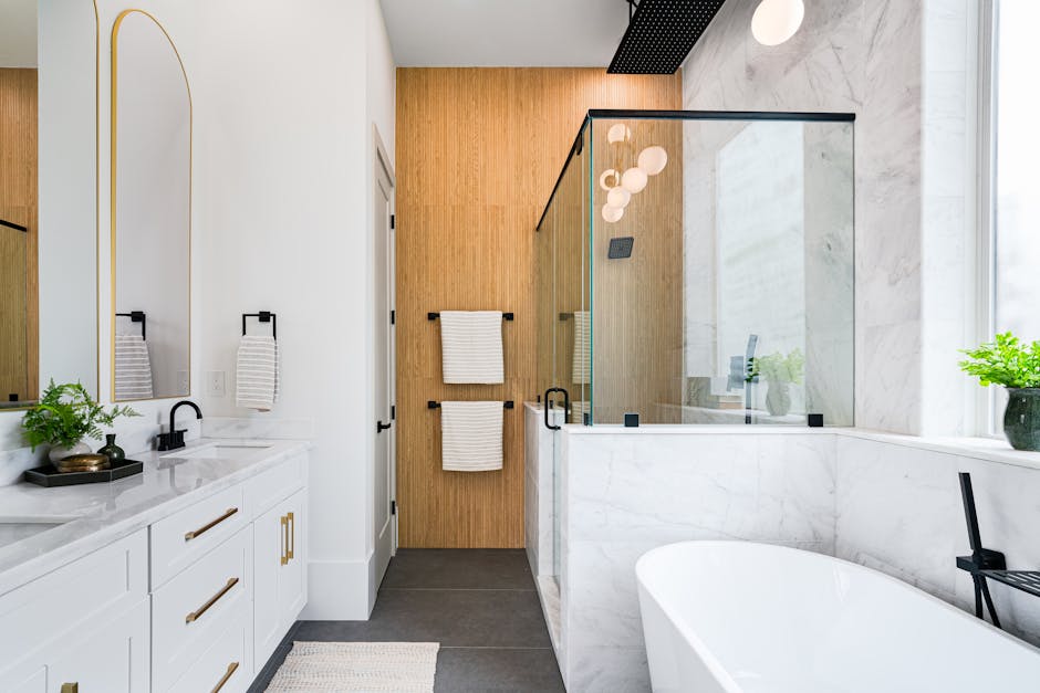 Spacious modern bathroom with marble, glass shower and elegant fixtures.