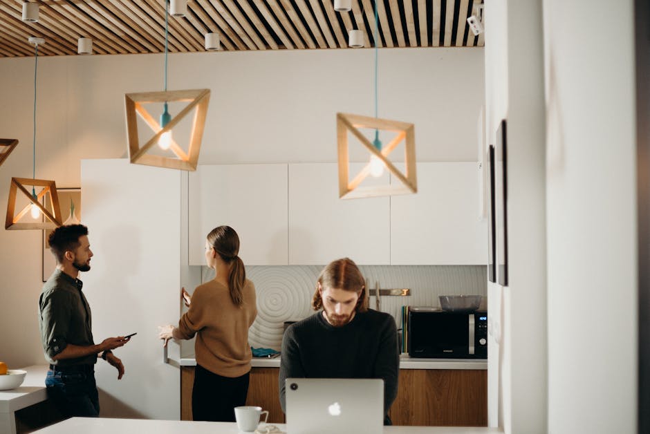 Three professionals working together in a chic, modern office kitchen.